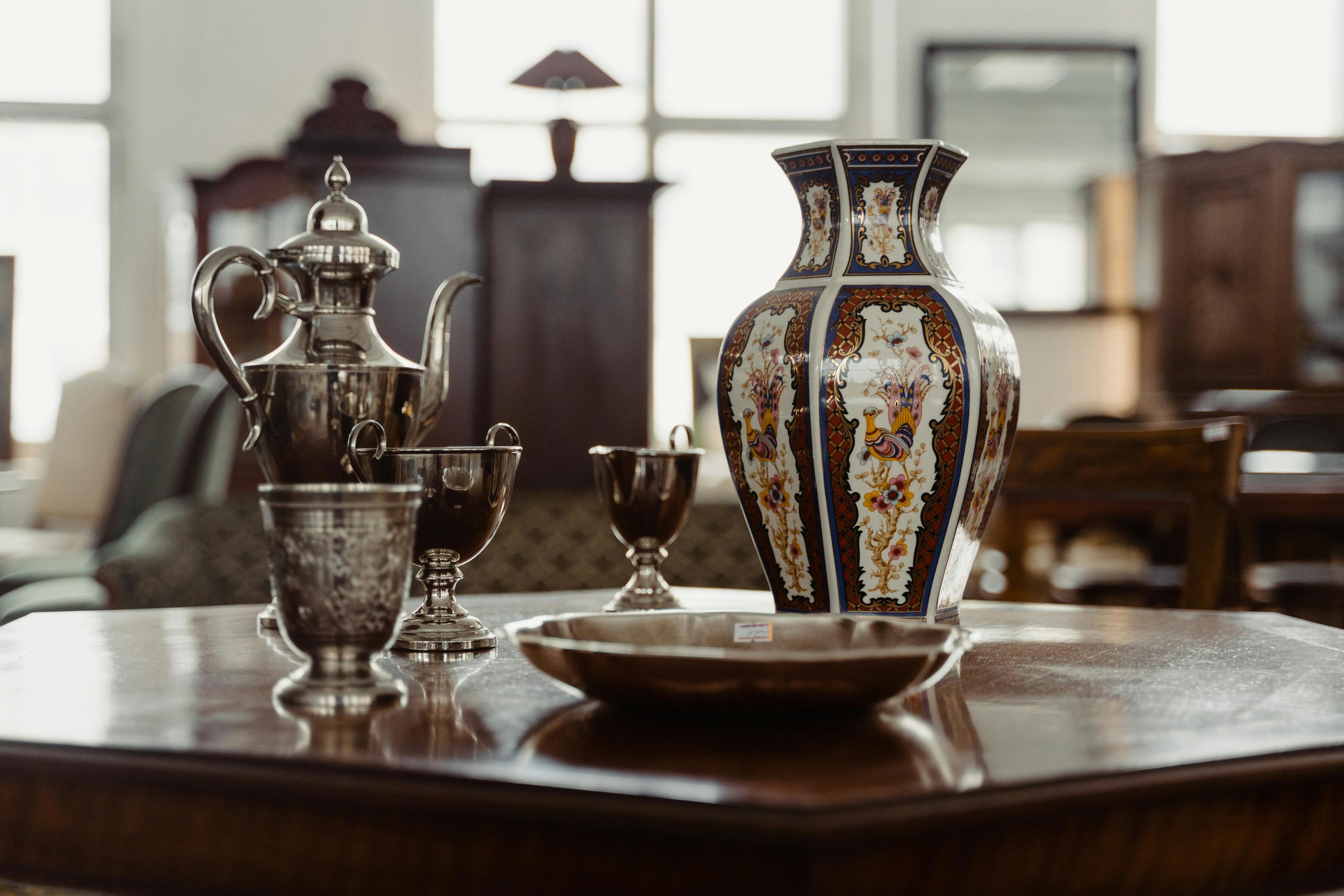 A collection of antique metalware and ceramics on a wooden table, capturing a vintage aesthetic.