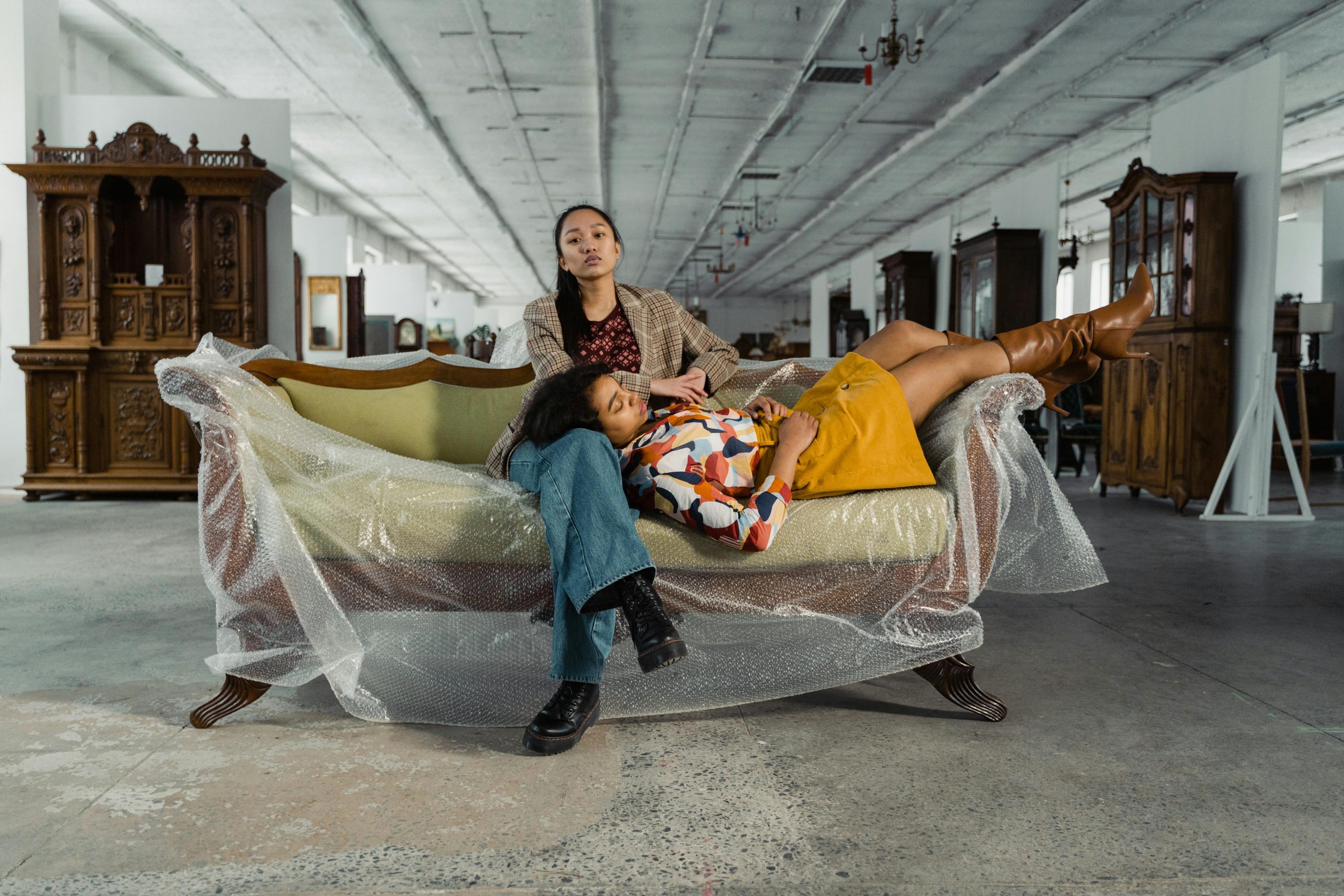 Two women relaxing on a vintage sofa in a retro furniture store.